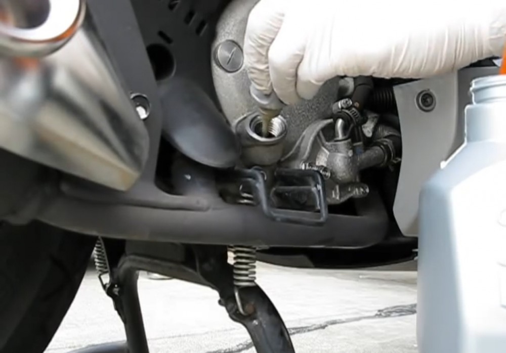 Thợ sửa xe máy đang thay nhớt cho xe tay ga